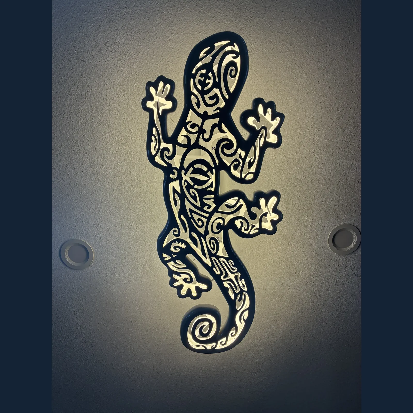 Gecko-shaped illuminated ceiling fixture with nearby recessed lights.